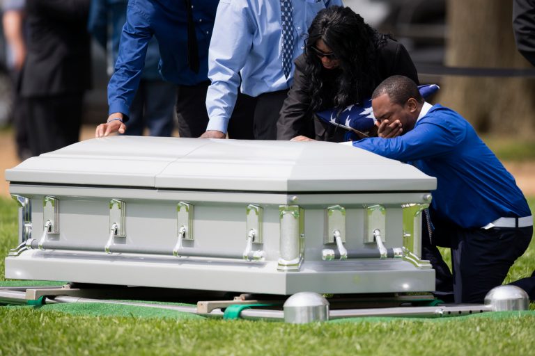 Sharon Blair, second from right, mother of U.S. Navy Petty Officer 2nd Class Mark Mayo, of Hagerstown, Md., puts her hand on her sons casket during his burial at Arlington National Cemetery in Arlington, Va., Friday, April 25, 2014.  Mayo was killed aboard the USS Mahan at Naval Station Norfolk, Va., after he dove in front of another sailor to protect her from a civilian truck driver who had seized her gun. Mayo was awarded the Navy Marine Corps Medal, the highest non-combatant decoration for heroism by a sailor or Marine. (AP Photo/ Evan Vucci)