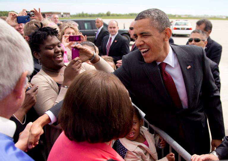 President Barack Obama greets people waiting for him on the tarmac as he arrives on Air Force One at Rickenbacker International Airport, Sunday, May 5, 2013, in Columbus, Ohio, en route to speak at the Ohio State University spring commencement. (AP Photo/Carolyn Kaster)