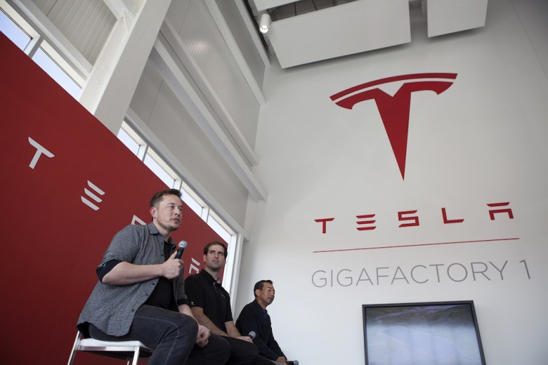 Billionaire Elon Musk, chief executive officer of Tesla Motors Inc., left, speaks as Jeffrey Straubel, chief technical officer and co-founder of Tesla Motors Inc., center, and Yoshihiko Yamada, consultant at Panasonic Corp., look on during a press event at Tesla's new Gigafactory in Sparks, Nevada, U.S., on Tuesday, July 26, 2016. Tesla officially opened its Gigafactory on Tuesday, a little more than two years after construction began. The factory is about 14 percent complete but when it's finished, it will be about 10 million square feet, or about the size of 262 NFL football fields. 
