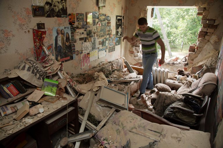 Eugeny Vaschenko walks through his room, damaged after shelling, in Maryinka village outside the city of Donetsk, eastern Ukraine Saturday, July 12, 2014. (AP Photo/Dmitry Lovetsky)