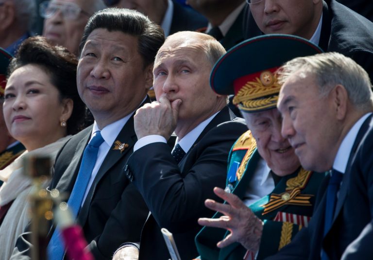Russian President Vladimir Putin, center, gestures while speaking with Chinese President Xi Jinping, second left, watching the Victory Parade marking the 70th anniversary of the surrender of Nazi Germany in World War II, in Red Square, Moscow, Russia, Saturday, May 9, 2015. Xi's wife Peng Liyuan is at left, Kazakh President Nursultan Nazarbayev is on the right, speaking to a veteran. (AP Photo/Alexander Zemlianichenko, Pool)
