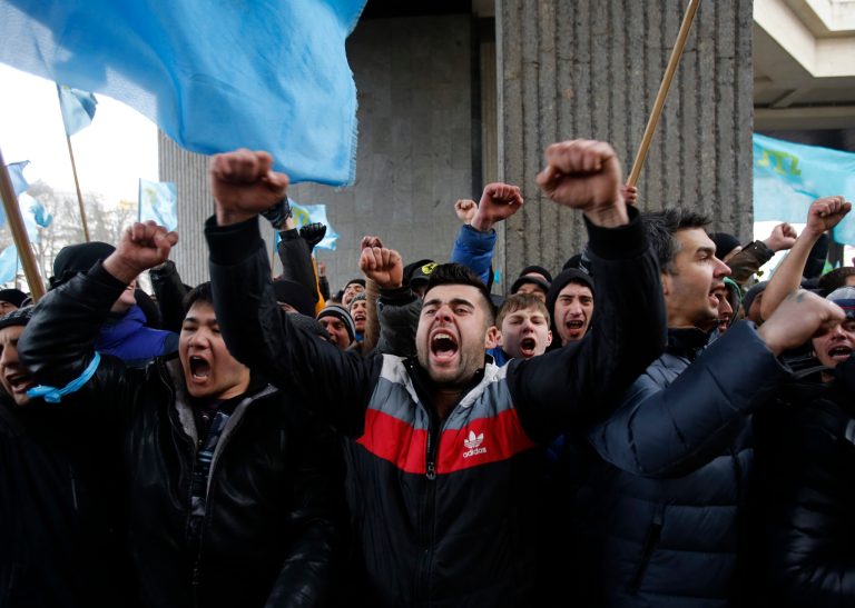 Crimean Tatars shout slogans during a protest in front of a local government building in Simferopol, Crimea, Ukraine, Wednesday, Feb. 26, 2014. More than 10,000 Muslim Tatars rallied in support of the interim government. That group clashed with a smaller pro-Russian rally nearby. Fistfights broke out between pro- and anti-Russian demonstrators in Ukraine's strategic Crimea region on Wednesday as Russian President Vladimir Putin ordered massive military exercises just across the border. (AP Photo/Darko Vojinovic)