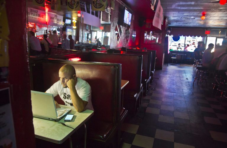 Steven Salinas works at his laptop in a booth at the family owned Subway Inn Bar on Thursday Aug. 14, 2014 in New York. The Subway Inn, one of Manhattan's infamous dive bars, is set to close later this month to make way for high-end luxury condos. But the family that has run the 77-year-old bar for the past 40 years is not going down easy. They are calling on the city to declare the building a landmark and stop the wrecking ball. (AP Photo/Bebeto Matthews)