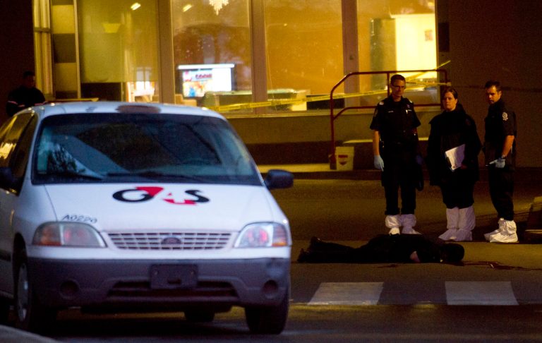   Police investigators look over the body of a shooting victim after three people were killed in an apparent attempted armed robbery at the University of Alberta in Edmonton, Canada on Friday, June 15, 2012. The robbery happened in the Hub Mall area, which is a combination of student residences and 54 shops. (AP Photo/The Canadian Press, Ian Jackson)  