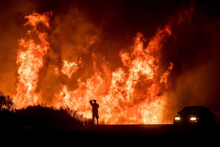 A motorist on Highway 101 watches flames from the Thomas fire leap above the roadway north of Ventura, Calif., on Wednesday, Dec. 6, 2017. (AP Photo/Noah Berger)