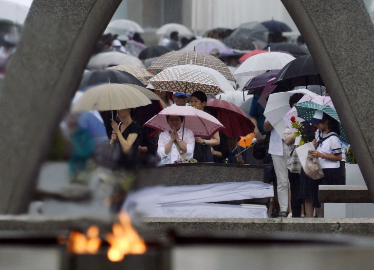 People pray for the atomic bomb victims in a rain at the Hiroshima Peace Memorial Park in Hiroshima, western Japan, early Wednesday, Aug. 6, 2014. Japan marked the 69th anniversary Wednesday of the atomic bombing of Hiroshima. (AP Photo/Kyodo News) JAPAN OUT, MANDATORY CREDIT