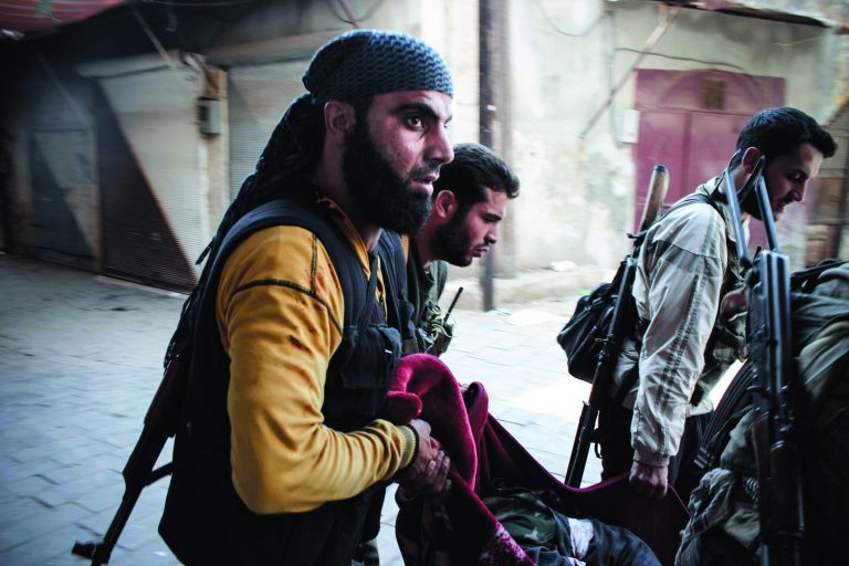 In this Tuesday, Oct. 30, 2012 photo, Syrian rebels carry a wounded comrade in a blanket away from the frontline in the town of Harem, Syria. (AP Photo/Mustafa Karali)
