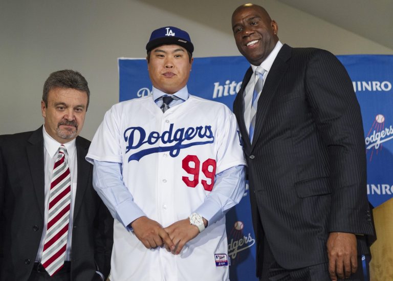   Los Angeles Dodgers general manager Ned Colletti, left, and co-owner Magic Johnson, right, present pitcher Ryu Hyun-jin, center, of South Korea, during a baseball news conference announcing his $36 million, six-year contract, Monday, Dec. 10, 2012, in Los Angeles. Ryu becomes the first player to go directly from the Korea Baseball Organization to the United States big leagues. (AP Photo/Damian Dovarganes)  