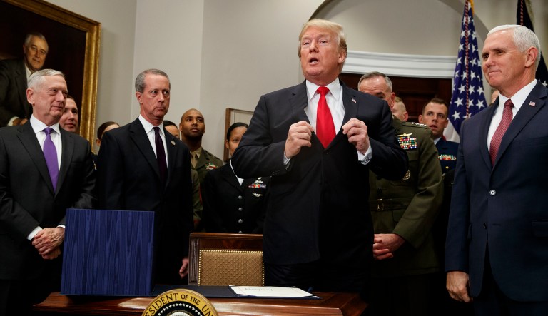 President Trump adjusts his jacket after signing the National Defense Authorization Act for Fiscal Year 2018, in the Roosevelt Room of the White House, Tuesday, Dec. 12, 2017, in Washington. (AP Photo/Evan Vucci)