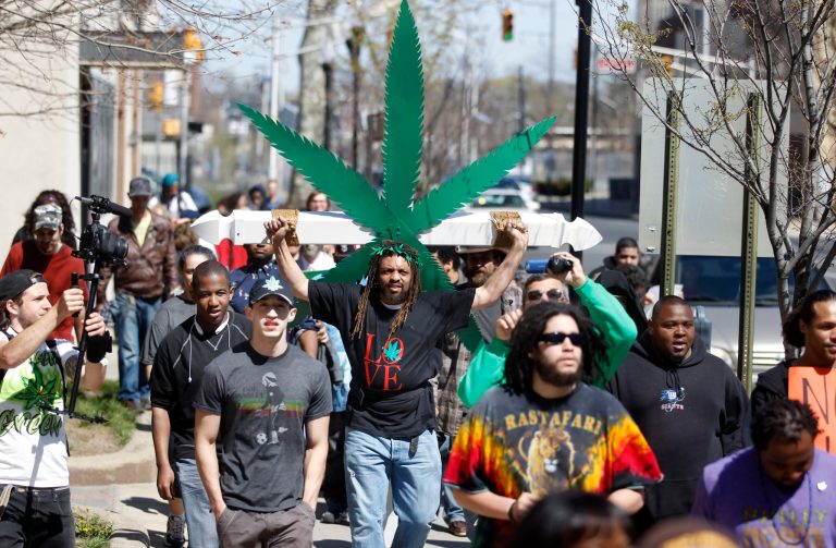 Ed Forchion, a pro-marijuana activist known as NJ Weedman, carries a large cross with likeness of a marijuana leaf as he walks with a group of activists along State Street in Trenton, N.J., Sunday, April 20, 2014. Dozens of activists and community members gathered in front of the Statehouse to show their support for legalizing marijuana. Sunday's rally was among many held nationwide to mark the traditional pot holiday of April 20, a day for marijuana activists to defiantly light up to protest their drug of choice being outlawed. (AP Photo/Mel Evans)