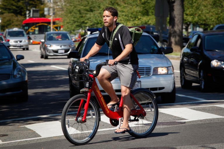 A Capital Bikeshare cyclist crosses a busy intersection on Capitol Hill. (Graeme Jennings/Examiner photo)