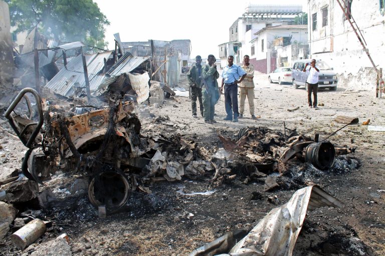 Somali soldiers look at the wreckage of the car that detonated the bomb near the entrance of Mogadishu's court complex, Mogadishu, Somalia, Sunday, April,14, 2013. Militants launched a serious and sustained assault on Mogadishu's main court complex Sunday, detonating at least two blasts, taking an unknown number of hostages and exchanging extended volleys of gunfire with government security forces, witnesses said.(AP Photo/Farah Abdi Warsameh)