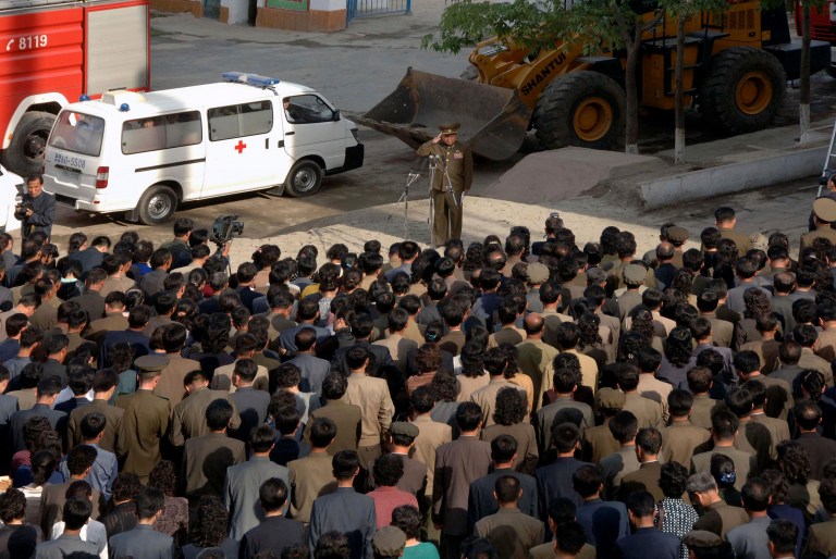 In this Saturday, May 17, 2014 photo released by the Korean Central News Agency (KCNA) and distributed by the Korea News Service, a North Korean official, center, salutes while apologizing in front of families of victims of an accident at an apartment construction site and local residents in Pyongyang, North Korea.  North Korean officials offered a rare public apology for the collapse of the apartment building under construction in Pyongyang, which a South Korean official said was believed to have caused considerable casualties that could mean hundreds might have died. (AP Photo/KCNA via KNS) JAPAN OUT UNTIL 14 DAYS AFTER THE DAY OF TRANSMISSION