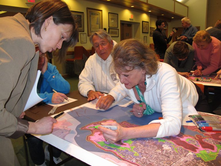 In this March 18, 2014 photo, Darlene Greene, left, reviews maps of Toms River N.J. that show flooding damage from Superstorm Sandy with Jeff Coley, center, and Jo-Ann Herbst. They were at a hearing at the Toms River municipal building for residents to make suggestions on how to protect against future storms. Ideas included building dunes, adding bulkheading, better securing boats and floating docks, and monitoring the slope of homeowners' properties to avoid channeling water into low-lying areas. (AP Photo/Wayne Parry)
