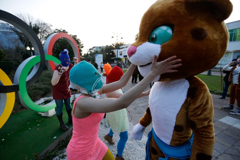 Pussy Riot member Nadezhda Tolokonnikova in the aqua balaclava, left, interacts with an Olympic mascot while the group perform next to the Olympic rings in Sochi, Russia, on Wednesday, Feb. 19, 2014. Cossack militia attacked the punk group with horsewhips earlier in the day as the artists - who have feuded with Vladmir Putin's government for years - tried to perform under a sign advertising the Sochi Olympics. (AP Photo/David Goldman)