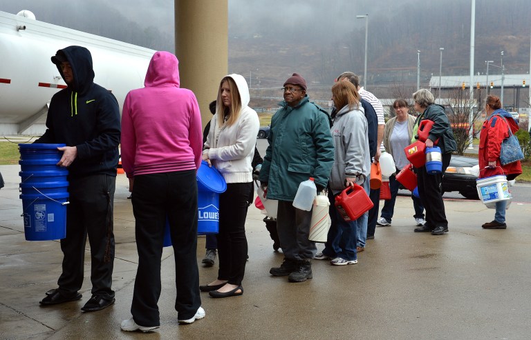 People wait in line for water from a 7500 gallon tanker truck brought in from Washington, Pa., on Jan. 10 at Riverside High School near Charleston, W.Va. (AP Photo/The Daily Mail, Craig Cunningham)