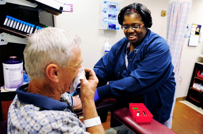 In this March 30, 2012 photo Allison Mitchell draws blood from Dwight Beeson at Harry S. Truman Memorial Veterans' Hospital in Columbia, Mo. Mitchell is one of nearly 300 Columbia College students who earned two-year associate degrees after the school tracked them down once they had left campus. The degree-completion program, known as Project Win-Win, began as a pilot project but has since expanded to more than 60 schools in nine states. (AP Photo/Columbia Daily Tribune, Ryan Henriksen)
