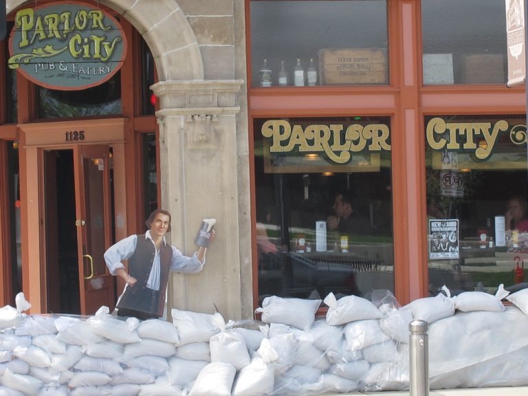 FILE - In this May 31, 2013, file photo, sandbags are piled around the Parlor City Pub and Eatery in Cedar Rapids, Iowa, where workers placed a cardboard cutout of a man drinking beer. Congress is on the cusp of passing its first infrastructure bill of the year. The Senate is expected to vote Thursday, May 22, 2014, on a $12.3 billion water resources bill that authorizes 34 water projects, from managing flood risks in Cedar Rapids, Iowa, and environmental restoration in Louisiana to dredging Boston Harbor.  (AP Photo/Ryan J. Foley, File)