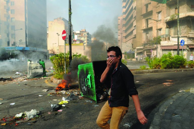 A man covers his mouth as he passes burning garbage containers laid by Sunni protesters, angry at the killing of Brig. Gen. Wissam al-Hassan, to block roads, in Beirut, Lebanon, Saturday, Oct. 20, 2012. Lebanese security officials say angry protesters have closed roads around the country to protest the bombing that killed a top security official and seven other people.(AP Photo/Ahmad Omar)