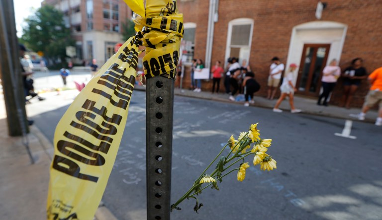 On Sunday, Aug. 13, 2017, police tape and flowers mark the site where a car plowed into a crowd of people protesting a white nationalist rally on Saturday in Charlottesville, Va. (AP Photo/Steve Helber)