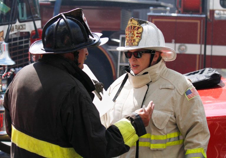 San Francisco fire chief Joanne Hayes-White, right, talks with another fireman by a fire at a commercial building in the Mission District Thursday, Sept. 4, 2014, in San Francisco. San Francisco fire officials say crews battled a five-alarm blaze at a two-story commercial building.  At least one firefighter and three civilians have been treated for smoke inhalation. The fire apparently began inside a retail store and quickly grew from two to five alarms in an hour. (AP Photo/Eric Risberg)