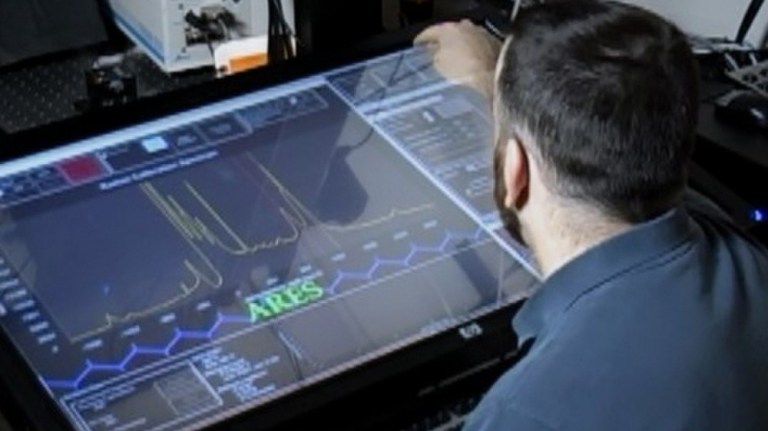 A materials researcher examines experimental data on the ARES artificial intelligence planner developed by the Air Force Research Laboratory to design, execute and analyze experiments at a faster pace than traditional scientific research methods. 