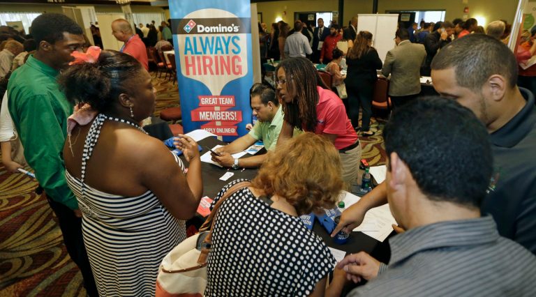 In this photo taken Wednesday, July 15, 2015, job seekers listen as Kaysara Mandry, center, talks about job opportunities at the Domino's booth during a job fair in Miami Lakes, Fla. (AP Photo/Alan Diaz)