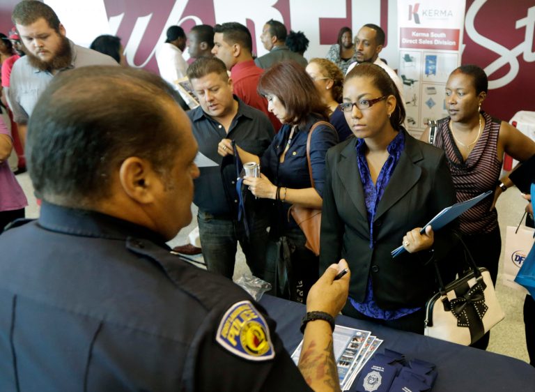 In this photo taken Tuesday, Aug. 19, 2014, job seeker Migdalia Feliz, of Miramar, Fla., third from right, listens to detective William DeJeus, left, of the Fort Lauderdale Police Department, at a job fair in Sunrise. Fla. The Labor Department reports on the number of people who applied for unemployment benefits last week on Thursday, Sept. 18, 2014. (AP Photo/Alan Diaz)
