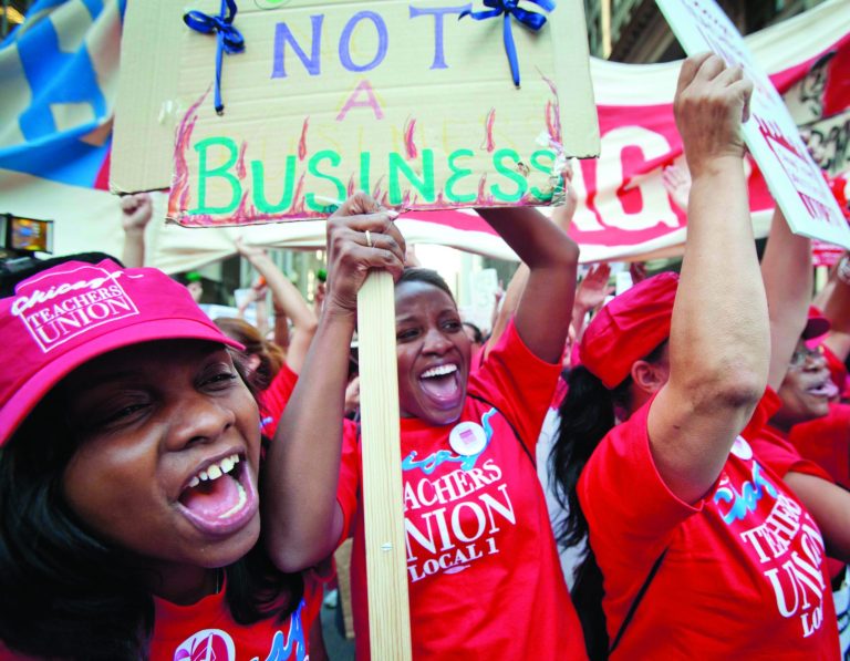 Public school teachers cheer as Chicago Teachers Union President Karen Lewis, unseen, arrives unexpectedly to address a rally of thousands of teachers gathered for the second consecutive day outside the Chicago Board of Education district headquarters on Tuesday, Sept. 11, 2012 in Chicago. Teachers walked off the job Monday for the first time in 25 years over issues that include pay raises, classroom conditions, job security and teacher evaluations. (AP Photo/Sitthixay Ditthavong)
