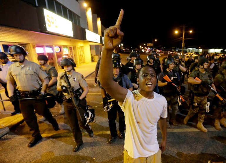 A man is moved by a line of police as authorities disperse a protest in Ferguson, Mo., early Wednesday. (AP/Charlie Riedel)