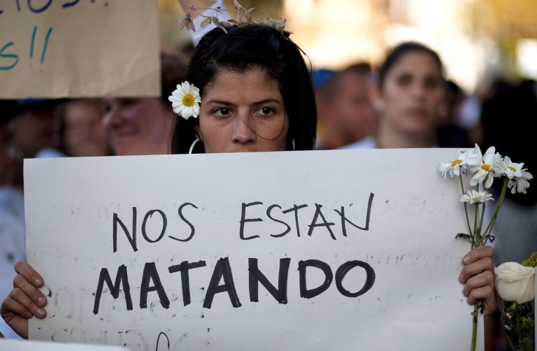 An opposition demonstrator holds a poster that reads in Spanish 