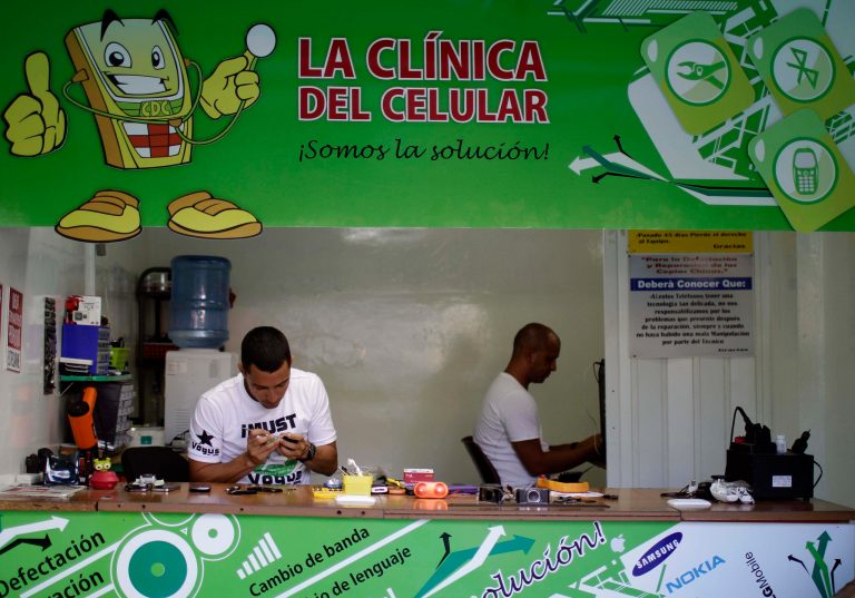   ADVANCE FOR USE SUNDAY, JUNE 17, 2012 AND THEREAFTER - In this June 13, 2012 photo, Javier E. Matos, left, repairs a phone at The Cell Phone Clinic, a private business in Havana, Cuba. For decades, Communist-run Cuba has essentially been free of commercial advertising. But it's a knotty problem for thousands of budding entrepreneurs who have embraced President Raul Castro's push for limited free-market reform. So they're turning to guerrilla marketing. (AP Photo/Franklin Reyes)  