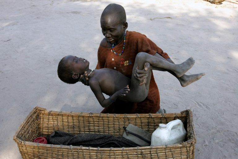   FILE - In this Dec. 21, 2005 file photo, a mother gently places her son in a basket as she takes him to a Medecins Sans Frontieres clinic after he contracted malaria, in Lankien, Southern Sudan. The fight against malaria is slowing down with a dramatic drop in the number of protective bednets distributed last year, even as health officials insist they will try to meet their ambitious target of eliminating deaths from the parasitic disease by the end of 2015. (AP Photo/Karel Prinsloo, File)  