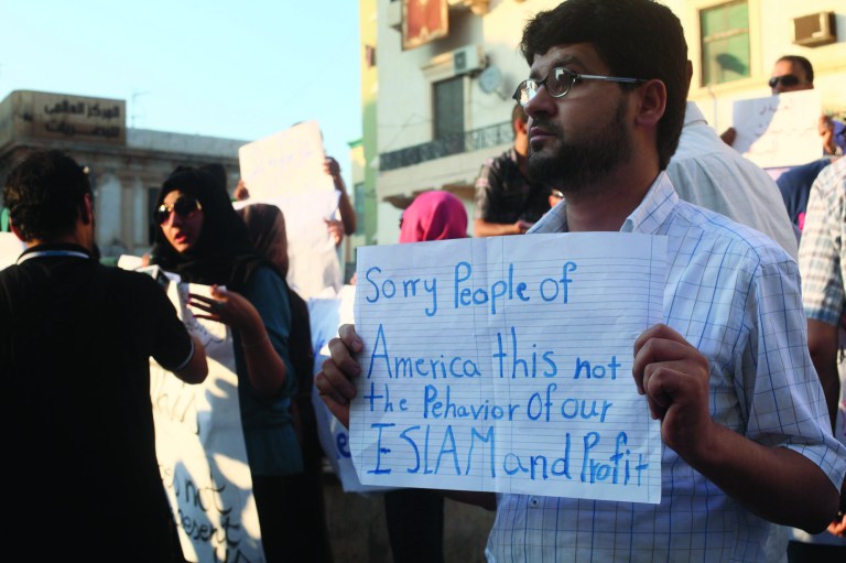 FILE - In this Wednesday, Sept. 12, 2012 file photo, a Libyan man holds a placard in English during a demonstration against the attack on the U.S. consulate that killed four Americans, including the ambassador, in Benghazi, Libya. The vast majority of Muslims have not taken to the streets over a film mocking the Prophet Muhammad, and behind the visible public anger a more measured debate is taking place over how much free speech is acceptable in the Muslim world. While many do yearn for more openness, few if any will go as far as accepting the right to blaspheme as the ultimate test of freedom of speech. (AP Photo/Ibrahim Alaguri, File)