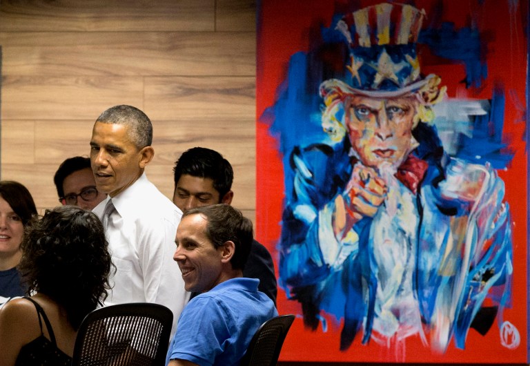 President Barack Obama stands next to a painting of 