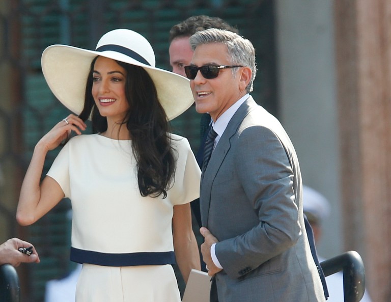 George Clooney, flanked by his wife Amal Alamuddin, arrives at the city hall for their civil marriage ceremony in Venice, Italy, Monday, Sept. 29, 2014. George Clooney married human rights lawyer Amal Alamuddin Saturday, the actor's representative said, out of sight of pursuing paparazzi and adoring crowds. (AP Photo/Luca Bruno)