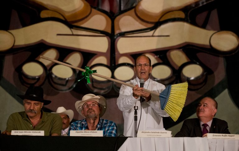 Father Alejandro Sololinde holds up a broom marked with a green ribbon as he urges people to support vigilante groups' efforts to sweep clean the country, during a national meeting of self-defense groups, in Mexico City, Wednesday, May 28, 2014. Other speakers at the meeting included Michoacan vigilante leaders Jose Manuel Mireles, left, and Hipolito Mora, second left, as well as Ernesto Ruffo, right.  Activists and social representatives announced Wednesday their intention to form a network of self-defense forces on a national scale that will denounce and confront violence. The network will shun the use of weapons. (AP Photo/Rebecca Blackwell)