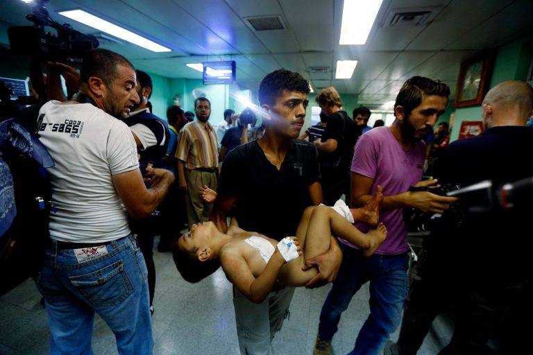 A Palestinian man carries a child, wounded in an Israeli strike on a compound housing a U.N. school in Beit Hanoun, in the northern Gaza Strip, cries at the emergency room of the Kamal Adwan hospital in Beit Lahiya, Thursday, July 24, 2014. Israeli tank shells hit the compound, killing more than a dozen people and wounding dozens more who were seeking shelter from fierce clashes on the streets outside. Gaza health official Ashraf al-Kidra says the dead and injured in the school compound were among hundreds of people seeking shelter from heavy fighting in the area. (AP Photo/Lefteris Pitarakis)