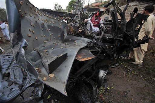 A Pakistan rescue worker looks at a vehicle targeted by terrorists in Peshawar, Pakistan on Monday, Sept. 3, 2012.  A suicide bomber rammed a car filled with explosives into a U.S. government vehicle in northwestern Pakistan on Monday, killing two Pakistanis and wounding 19 others, including two Americans, officials said. (AP Photo/Mohammad Sajjad)