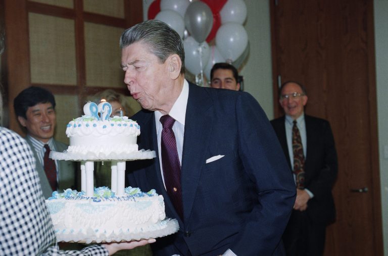 Former President Ronald Reagan blows out the candles on his 82nd birthday cake at his Los Angeles office. The former chief of state's office staff had an impromptu party for him. (AP Photo/Nick Ut)