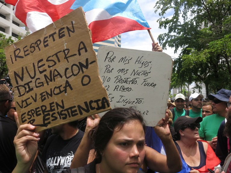 People protest looming austerity measures amid an economic crisis and demand an audit on the island's debt to identify those responsible, during the May Day march in San Juan, Puerto Rico, Monday, May 1, 2017. The signs read in Spanish, left, 