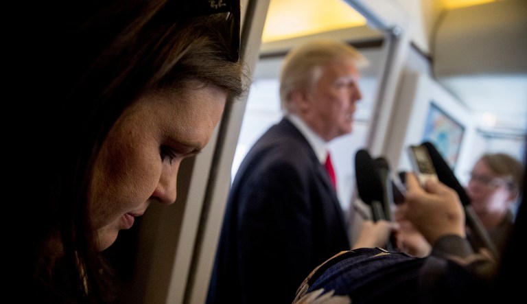 White House press secretary Sarah Huckabee Sanders, left, listens as President Trump speaks to reporters aboard Air Force One. (AP Photo/Andrew Harnik)