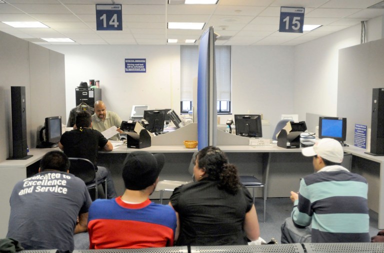 Kenneth Hamilton, seated behind desk, a senior document examiner at Maryland's Motor Vehicle Administration, checks the documents of Jose Augusto S. Faustino, seated at desk, Thursday, March 19, 2009 in Glen Burnie, Md. (AP Photo/ Steve Ruark)