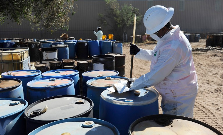 In this Tuesday, Sept. 15, 2015, photo, workers with Environmental Restoration take samples of contents of drums that had been abandoned at the former Ector Drum site in Odessa, Texas. (Mark Sterkell/Odessa American via AP) MANDATORY CREDIT