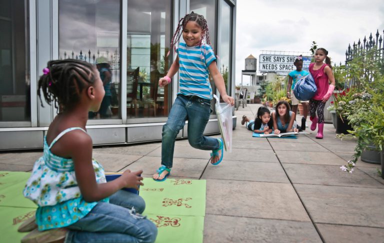   In this Wednesday, Aug. 7, 2013 photo, youngsters attending LitCamp, a summer reading program offered through the nonprofit literacy organization LitWorld, find sections of a rooftop patio for their independent reading, in New York's Harlem neighborhood. 