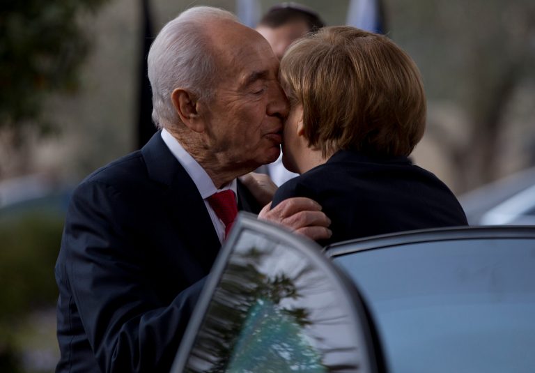 Israel's President Shimon Peres kisses German Chancellor Angela Merkel as she arrives to receive the Presidential Medal ceremony at the President's residence in Jerusalem,Tuesday, Feb. 25, 2014. The Presidential Medal is the highest civil medal given by the State of Israel. (AP Photo/Ariel Schalit2