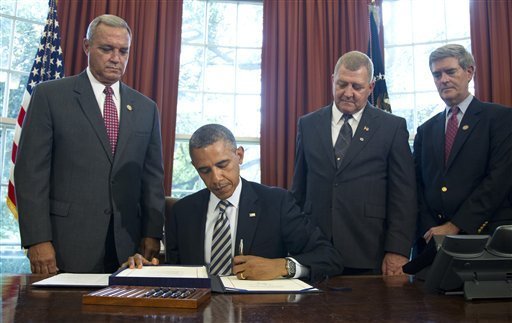 President Obama signs legislation directing the Department of Veterans Affairs to provide medical care to veterans who developed cancer or other illnesses after serving a Camp Lejeune, N.C., where jet fuel leaked into the drinking water for years. On Obama's right is Rep. Jeff Miller, R-Fla., chairman of the House Committee on Veterans Affairs. (AP Photo) 