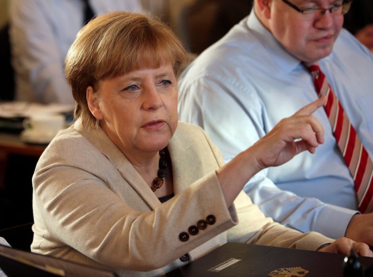 German Chancellor Angela Merkel, left, points as she and Peter Altmaier, Head of the Federal Chancellery, right, attend a cabinet meeting as part of a two day closed meeting of the German government at the Meseberg palace near Berlin, Germany, Thursday, Jan. 23, 2014. (AP Photo/Michael Sohn)