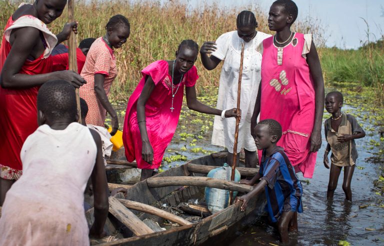A family of the Nuer ethnic group seeking medication and food, but who were planning to later return to their village in a Nuer rebel-controlled area, prepare to board a canoe to traverse a flooded area too deep to walk through, as they try to reach a makeshift camp for the displaced situated in the United Nations Mission in South Sudan (UNMISS) base in the town of Bentiu, South Sudan Saturday, Sept. 20, 2014. Seyoum Mesfin, the chairman of the South Sudan mediation process said Saturday there is renewed fighting in South Sudan between government and rebel troops and that it is a purposeful act aimed at derailing the next phase of the peace process. (AP Photo/Matthew Abbott)