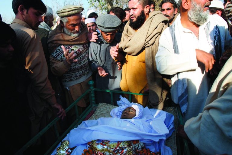 Pakistani villagers look at the body of health worker Hilal Khan, who was killed by gunmen, in Wahidgari, on the outskirts of Peshawar, Pakistan on Thursday, Dec. 20, 2012. Another victim from attacks on U.N.-backed anti-polio teams in Pakistan died on Thursday, bringing the three-day death toll in the wave of assaults on volunteers vaccinating children across the country to nine, officials said. (AP Photo/Mohammad Sajjad)